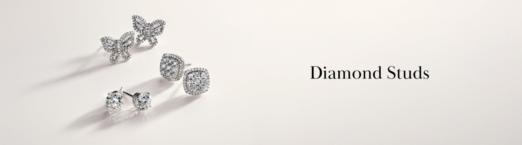 Three pairs of diamond stud earrings in various shapes—round, heart, and butterfly—are displayed on a neutral background with the text Diamond Studs to the right.