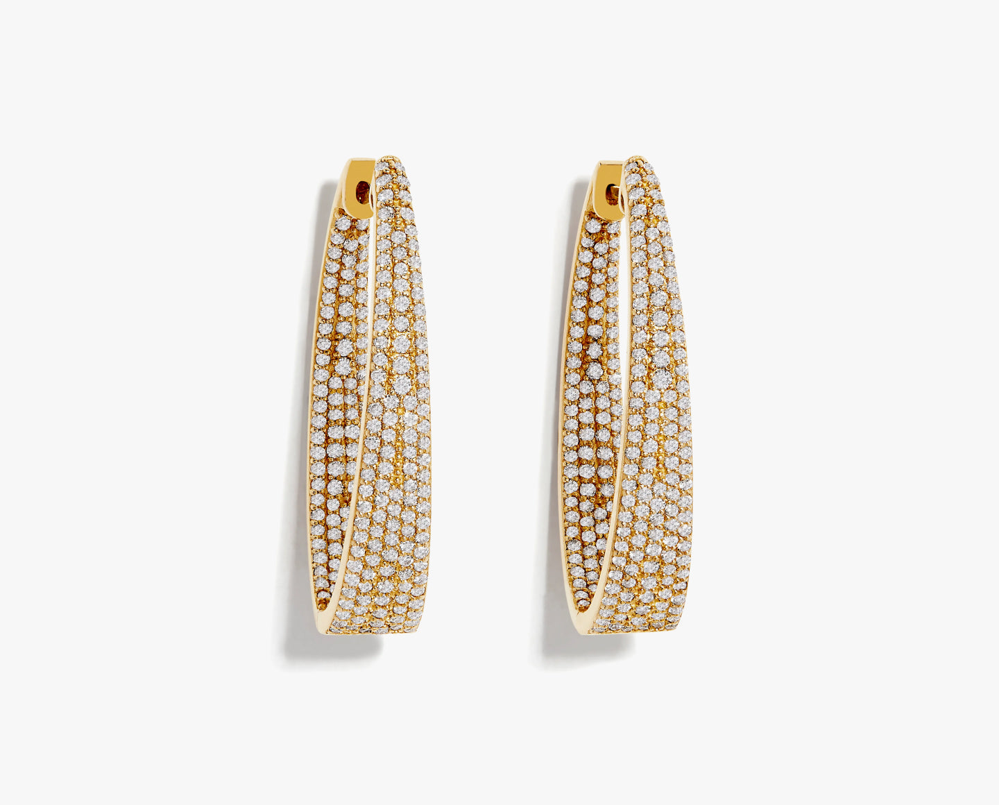 A pair of gold elongated hoop earrings, each encrusted with rows of small, sparkling white stones, displayed against a plain white background.