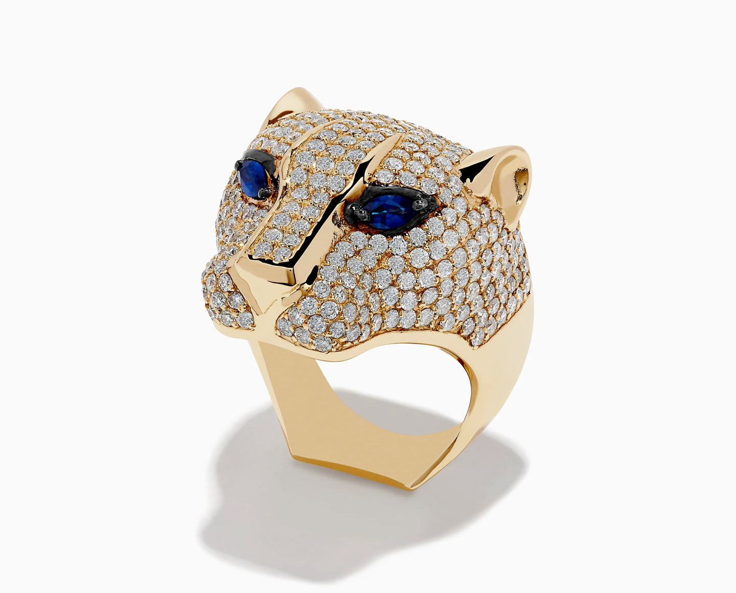 A gold ring shaped like a panther’s head, encrusted with small diamonds and featuring deep blue gemstone eyes, viewed on a plain white background.