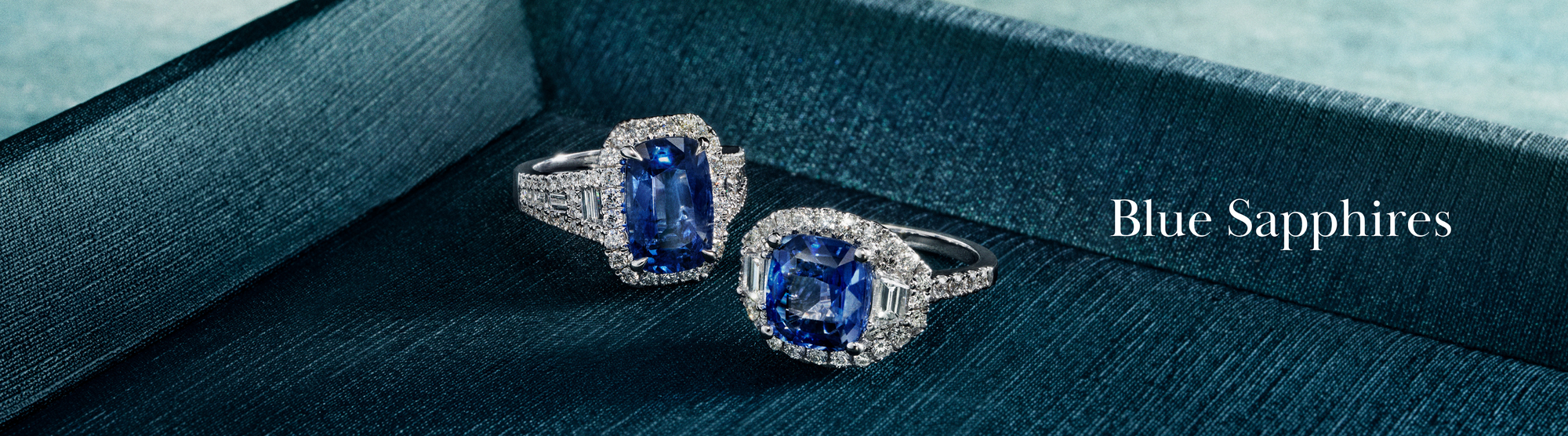 A diamond and blue sapphire bracelet stands upright on a reflective blue surface with the text Blue Sapphires beside it against a blurred blue background.